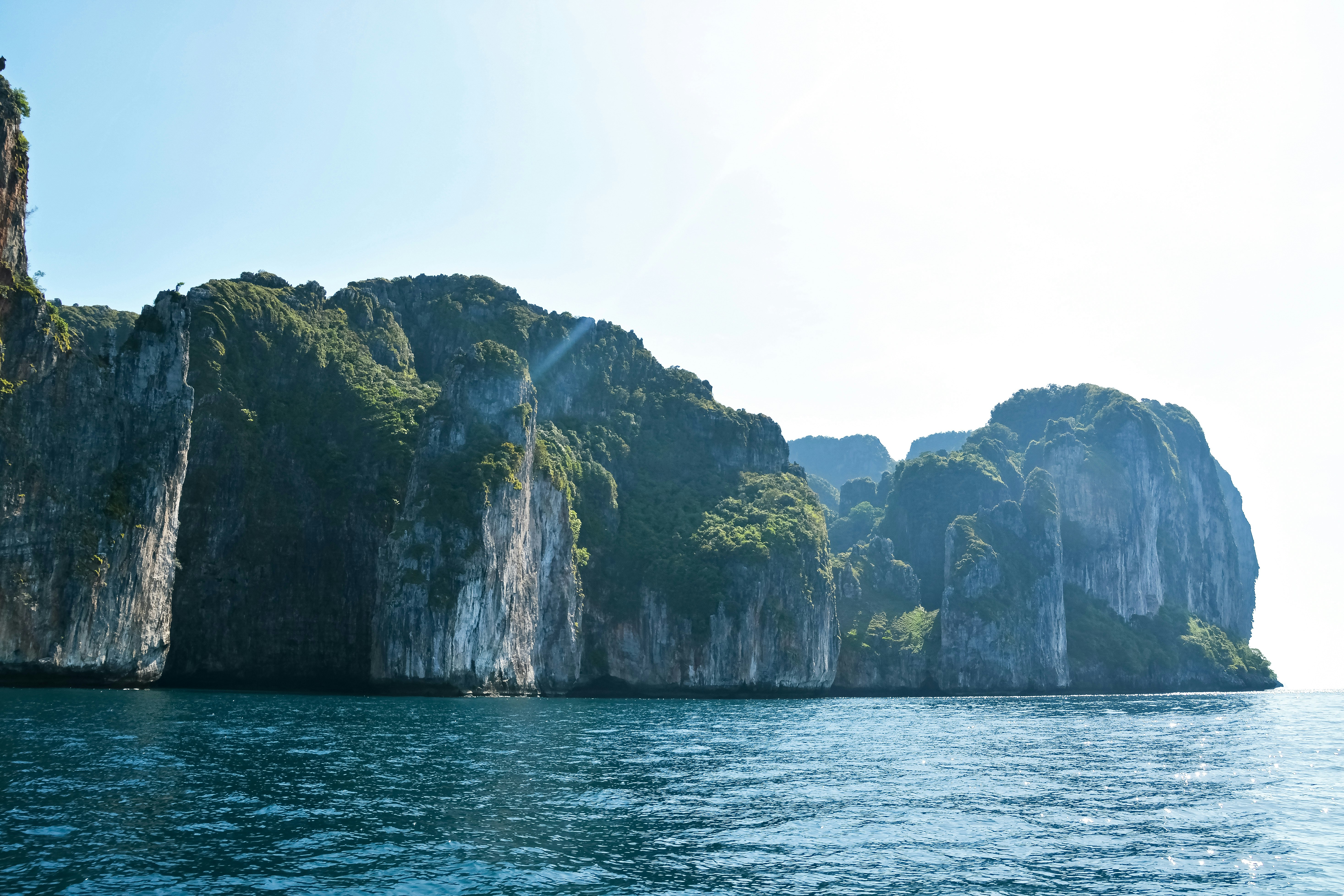 green and brown rock formation on sea during daytime